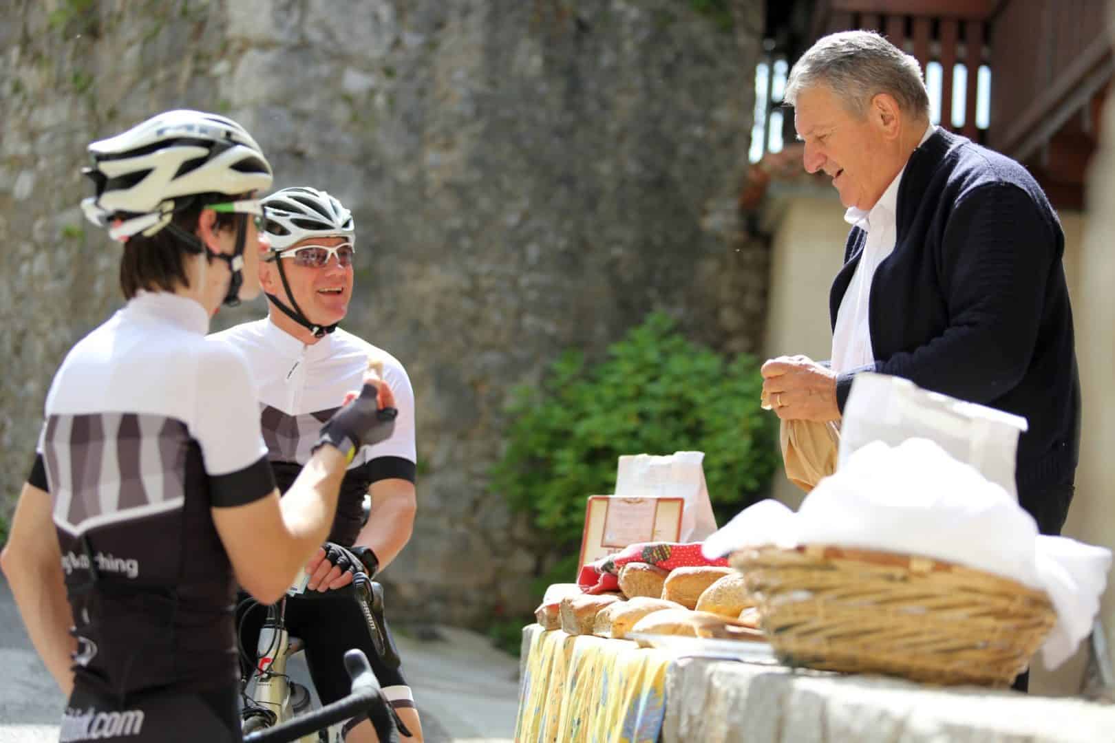 Slovenian people. Local selling bread at Štanjel village. Road cyclists touring Slovenia.