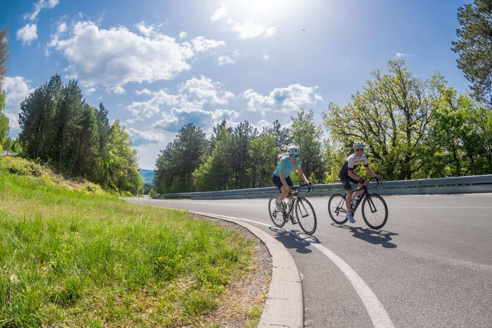 Couple cycling on road bikes in Slovenia. Perfect alpine road. Guided bike tour by RockVelo.