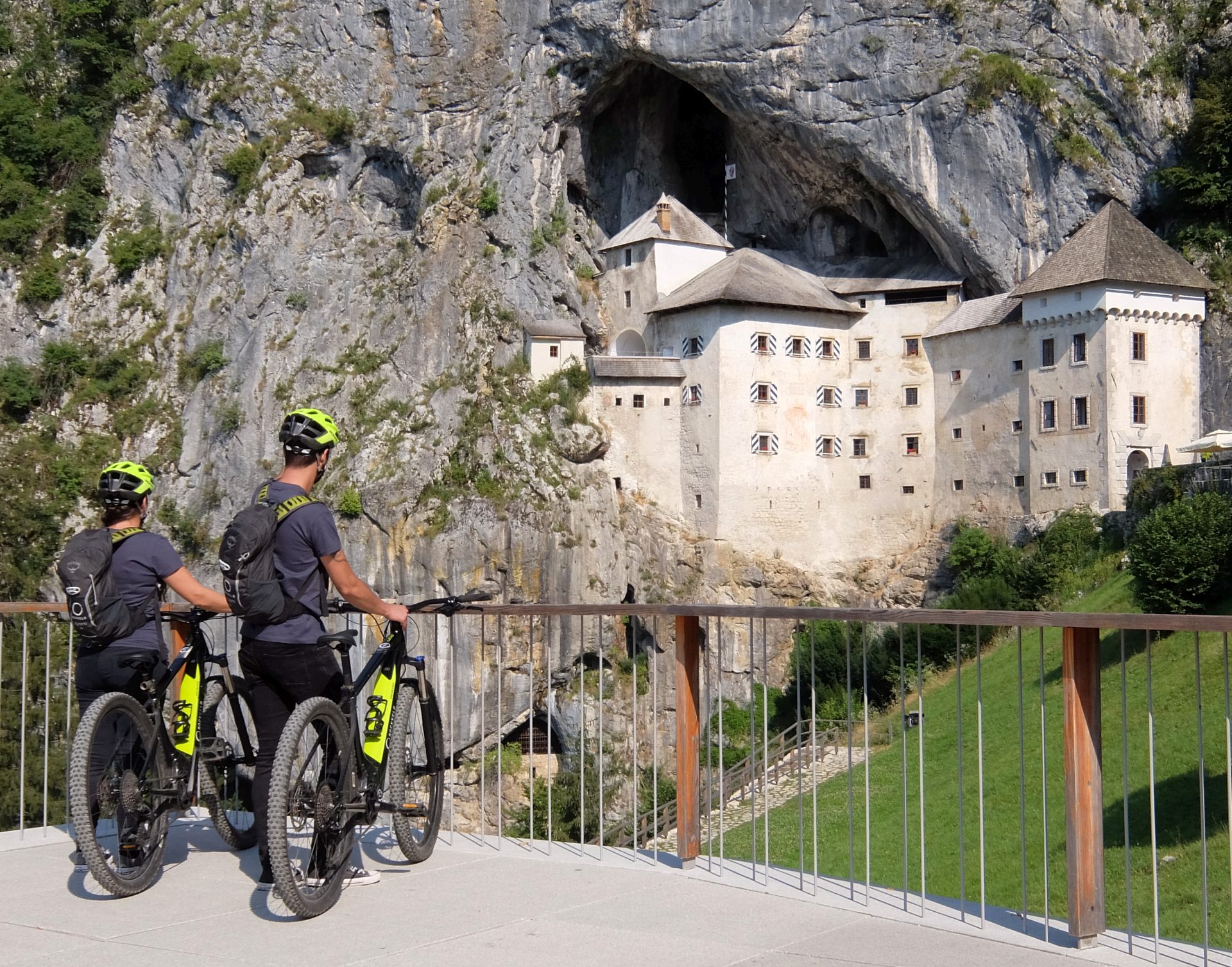 Two cyclists in front of Predjama Castle