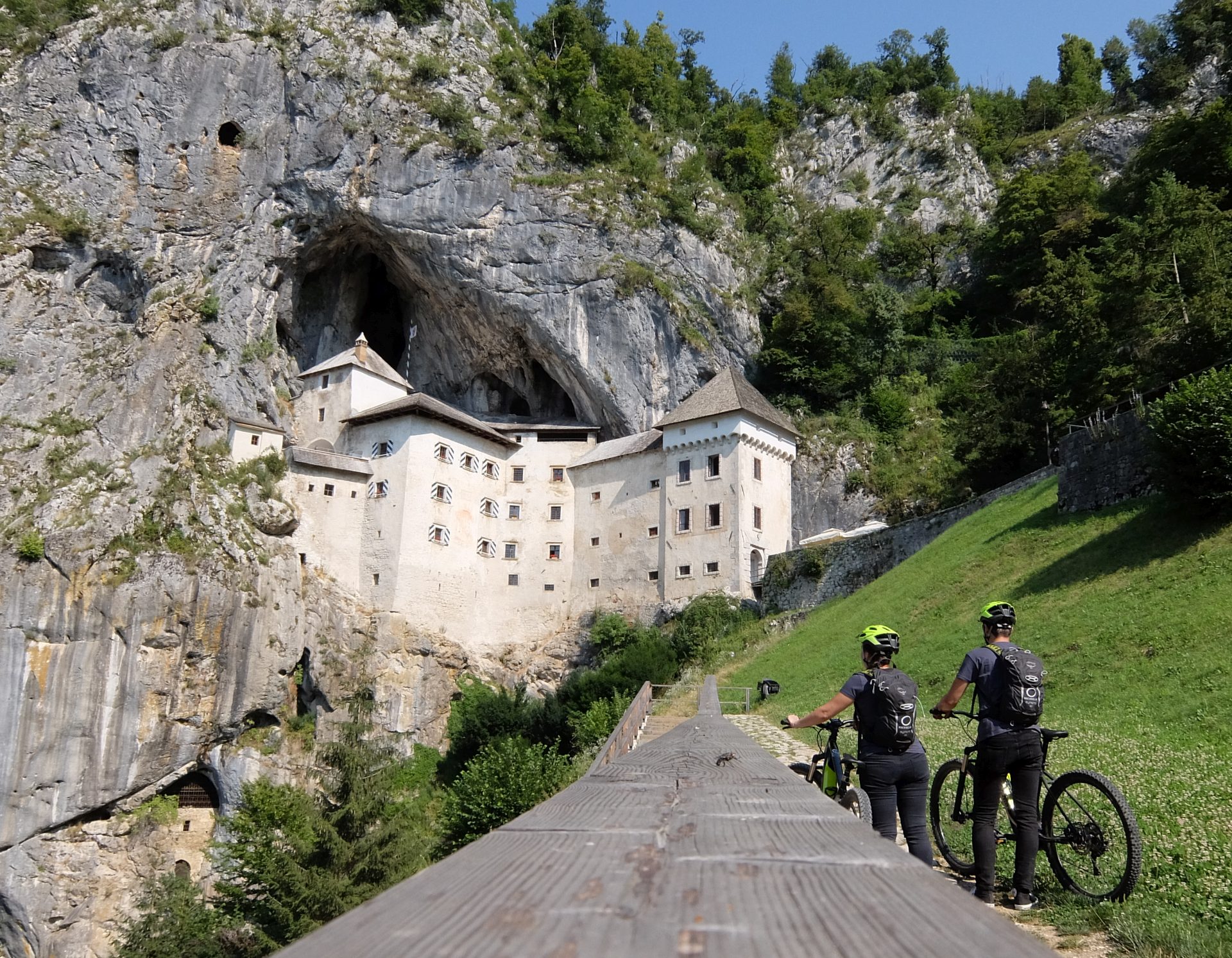 World famous Predjama Castle with cyclists in front riding e-bikes.